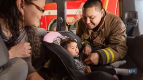 tribal car seat - still from video photo: fireman helping Native American mother with her child's car seat.